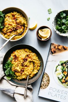 two bowls filled with food on top of a table next to a cookbook and spoons