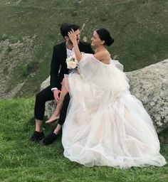 a man and woman sitting on top of a lush green field