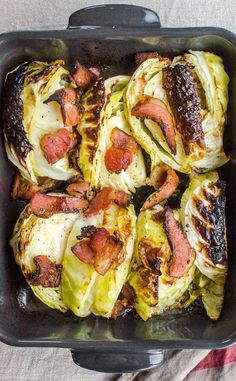 a casserole dish with meat and vegetables in it on a table cloth next to a fork