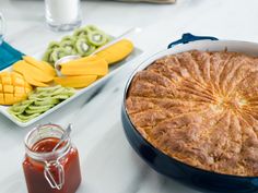 there is a pie in the pan on the table next to other food and drinks