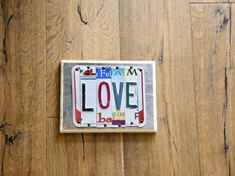 a license plate with the word love is displayed on a wood flooring surface in front of a wooden wall