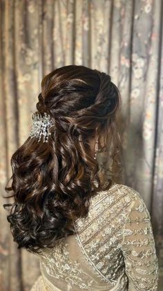 the back of a woman's head with curly hair and an intricate brooch