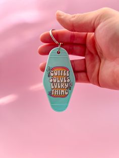 a hand holding a keychain that says coffee solves every thing on it