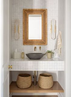 a bathroom sink with two baskets under it and a mirror above the sink on the wall