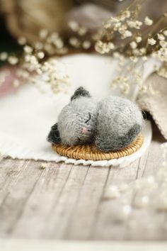 a small stuffed animal laying on top of a wooden table next to some white flowers