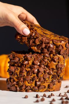 a person is picking up some chocolate chip pumpkin bread