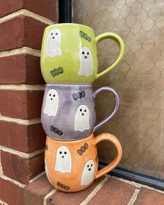 three ghost mugs are stacked on top of each other in front of a window