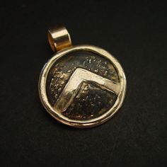 "This Spartan Shield necklace is hand sculpted, domed and beaten up to look like it has been on a battlefield. The letter lambda (Λ), standing for Laconia (administrative capital of Sparta) or Lacedaemon (ancient name for the city of Sparta), which was painted on the Spartans' shields, was first adopted in the 420s BC, and quickly became a widely known Spartan symbol. Military families passed on their shields to each generation as family heirlooms. - Hand sculpted pendant - Solid yellow bronze a