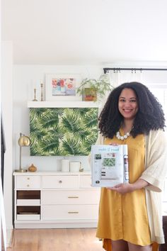 a woman in a yellow dress holding up a magazine