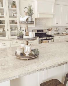 two tiered trays on the counter in a white kitchen with marble counter tops