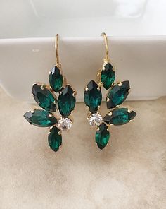 pair of green and white crystal earrings with gold tone earwires on beige background