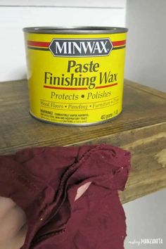 a can of minwax paste sitting on top of a wooden shelf next to a red cloth