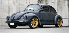 a gray and yellow volkswagen beetle parked in front of a concrete wall