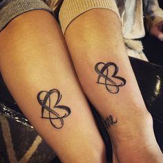 two people with matching tattoos on their legs, one has a heart and the other has an arrow