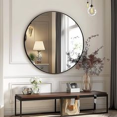 a living room with a large round mirror on the wall next to a wooden table