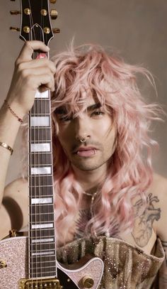 a man with long pink hair holding an electric guitar