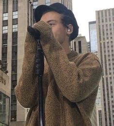 a man holding a microphone up to his face while standing in front of tall buildings