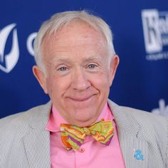 an older man wearing a pink shirt and striped jacket with a bow tie smiling at the camera