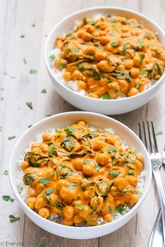 two bowls filled with rice and chickpeas on top of a wooden table next to silverware