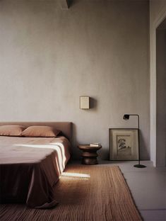 a bed sitting in a bedroom next to a wall mounted light on the side of it