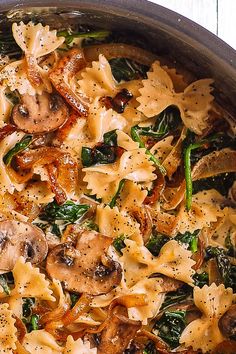 a pan filled with pasta and mushrooms on top of a wooden table