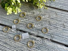 several rings are placed next to each other on a wooden table with greenery in the background