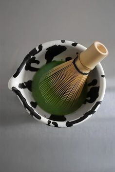 a whisk in a black and white bowl with cow print pattern on it