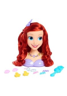 the little mermaid doll has red hair and is surrounded by plastic toys on a white surface