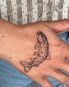 a person's hand with a fish tattoo on it