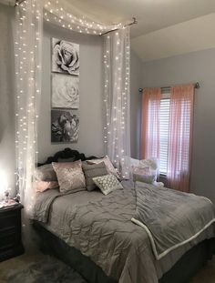 a bedroom with lights on the ceiling and a bed covered in grey sheets, pillows and blankets