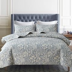 a bed with blue and white bedspread, pillows and pillow cases on it