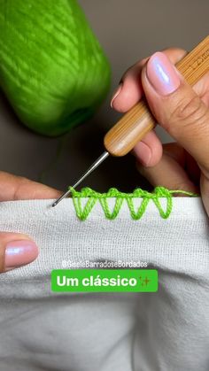 a woman is using a needle to crochet an object