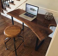 a laptop computer sitting on top of a wooden desk next to a stair case in a home