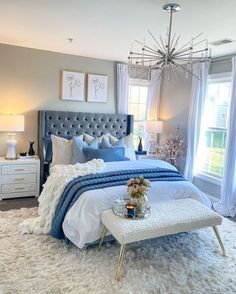 a bedroom decorated in blue and white with a chandelier