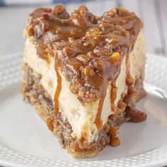 a piece of cake on a white plate with chocolate sauce and pecans in the middle