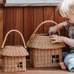 a little boy sitting on the floor next to a wicker basket