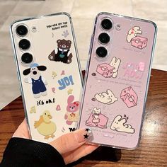 two clear cases with cartoon stickers on them, one is holding the other case