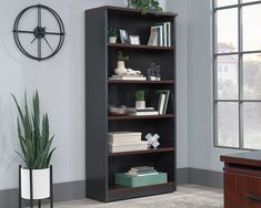 a book shelf with books and plants on it in a living room next to a window