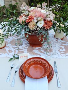 a table set with plates, silverware and flowers