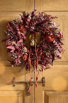 a wreath hanging on the front door of a house with red and purple flowers in it