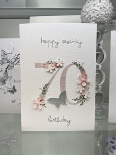 a white card with pink flowers and butterflies on it that says happy seventyth birthday