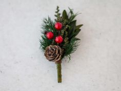 a boutonniere with pine cones, berries and greenery on the side