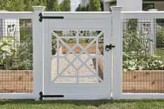 a white gate with metal bars on the top and bottom, in front of a house