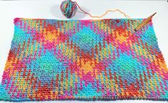 a crocheted blanket with yarn and knitting needles