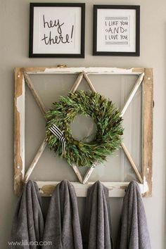 two framed pictures hang on the wall next to a wreath and towel rack with towels