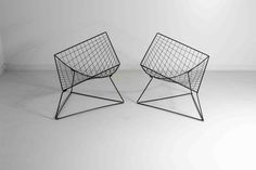 two black wire chairs sitting next to each other on top of a white floor in front of a wall