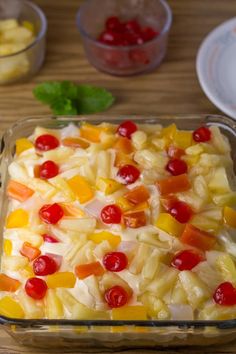 a casserole dish filled with fruit and veggies on a wooden table