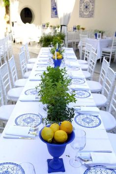 a long table with blue and white plates, lemons and parsley in a bowl