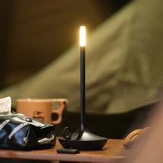 a candle is sitting on a table next to a bag and coffee cup with a person sleeping in the background