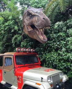 a dinosaur head hanging over the top of a jeep